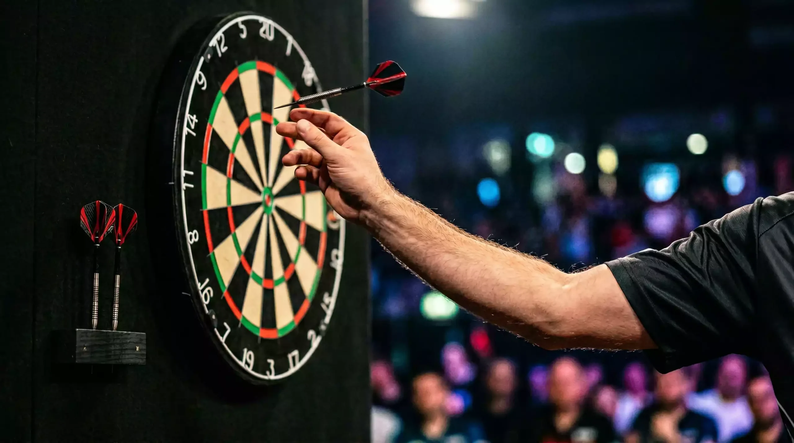 Darts Wettarten – Spieler wirft am Oche auf Dartscheibe